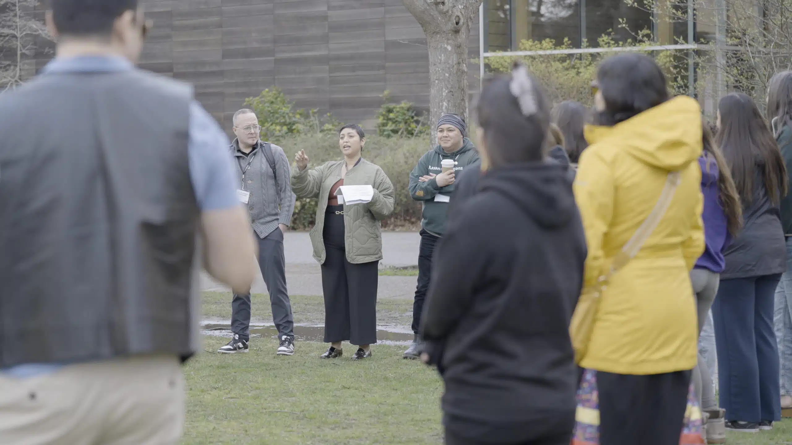 A group of students standing in a talking circle outside